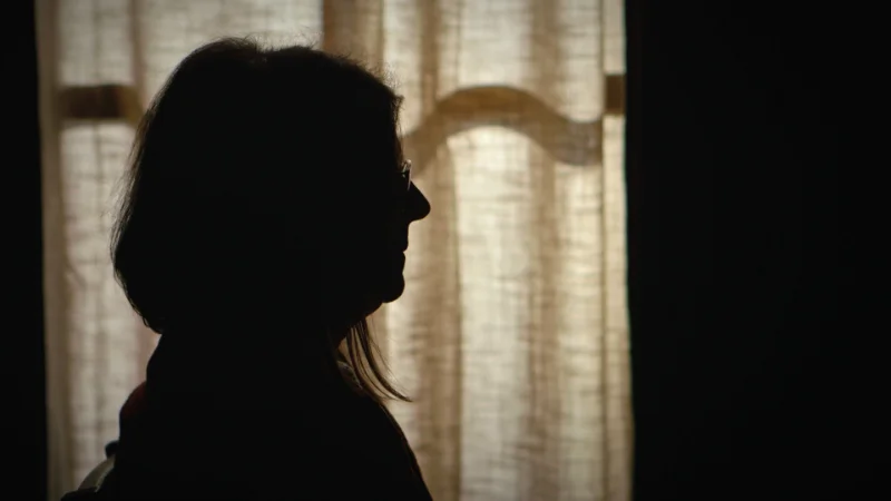 Silhouette einer Frau im Gegenlicht vor einem hellen Vorhang
