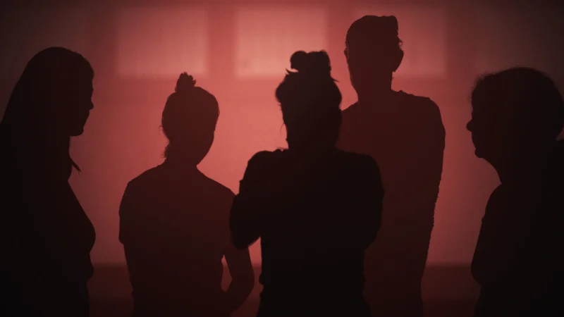 Silhouetten von fünf Menschen vor rotem Licht